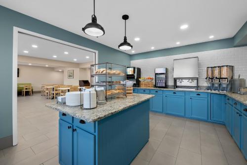 a large kitchen with blue cabinets and a cafeteria at Country Inn & Suites by Radisson, Near The National Sports Center, Coon Rapids, MN in Coon Rapids