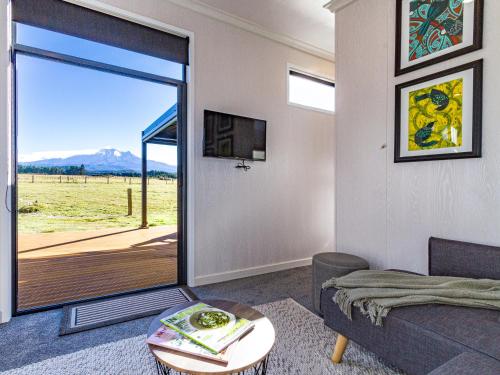 a living room with a couch and a sliding glass door at Mangateitei Views - Rangataua Tiny Home in Ohakune