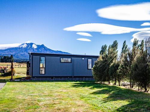 a house in a field with mountains in the background at Mangateitei Views - Rangataua Tiny Home in Ohakune