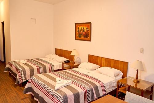a hotel room with two beds and two tables at Hotel Pacífico Talara in Talara