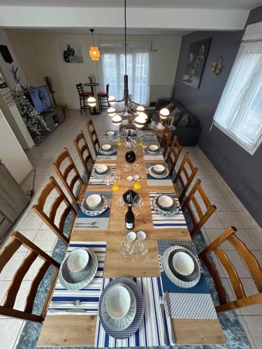 une grande table en bois avec des chaises et des assiettes. dans l'établissement Bienvenu au Karush, Proche château Chambord et Blois, à Mer