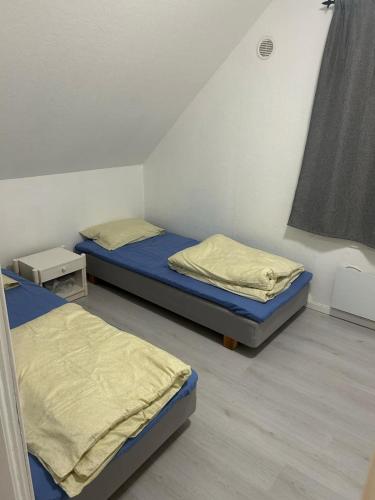 two twin beds in a room with a window at Leilighet med 3 soverom nær sentrum in Kristiansand