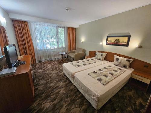 a hotel room with a bed and a television at Family Hotel Jeri in Velingrad