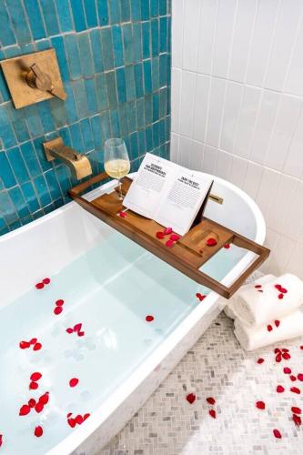 a tray with a glass of wine and a book on a bath tub at Paix Bleu- Heated Pool & Spa Pet Friendly in Galveston