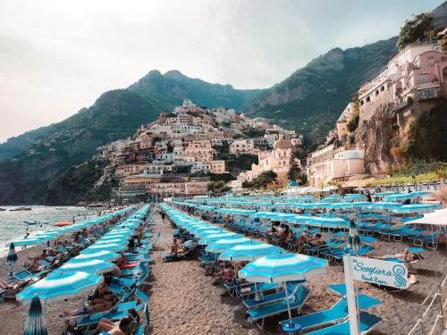 a beach with blue umbrellas and people on it at Maison Raphael Positano in Positano
