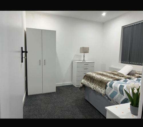 a white bedroom with a bed and a dresser at Luton Centrally Located Apartment v close London Luton Airport in Luton