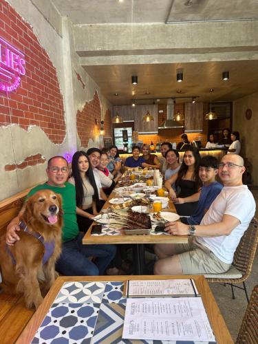 a group of people sitting at a table with a dog at Shorebreak Hostel San Juan La Union in san juan la union