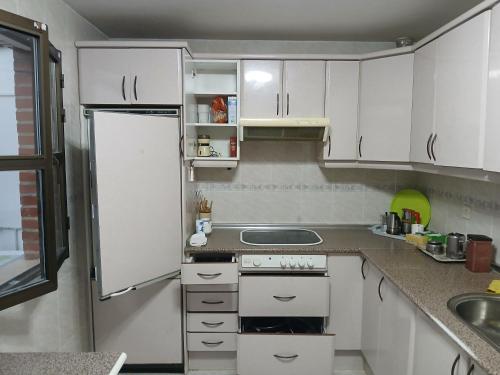 a small kitchen with white cabinets and a refrigerator at Habitacion Privada Triple Toledo in Toledo
