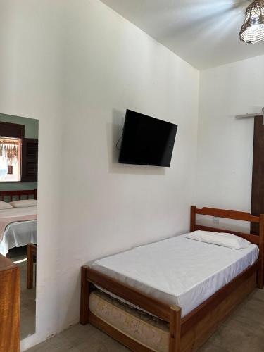 a bedroom with a bed and a tv on the wall at Vila Lua Aparts - Apartamento 1 in Jericoacoara