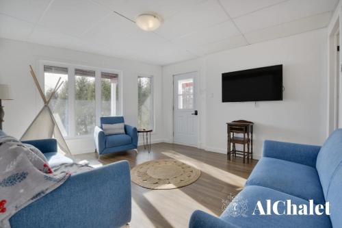 a living room with blue chairs and a flat screen tv at Älpha-M - magnifique vue sur le fleuve in Baie-Saint-Paul