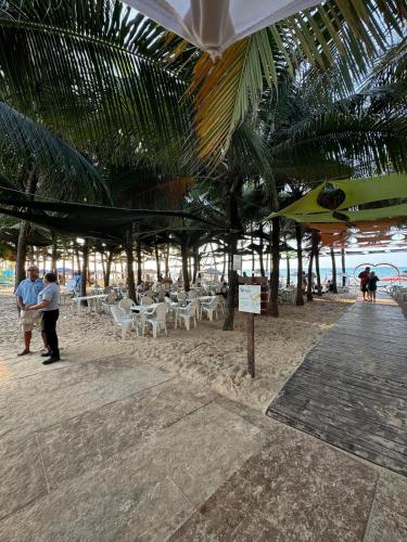 a group of people on a beach with chairs and umbrellas at Apartamento Beach place Cumbuco 100m da Praia in Caucaia