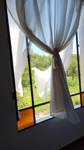 a window with a curtain and a view of a field at Casas de Época - Arrebol in Charbonier
