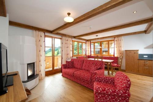 a living room with a red couch and a table at Tauernchalets in Grossarl