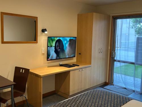 a room with a desk with a television on it at Shelby Motor Lodge in Invercargill