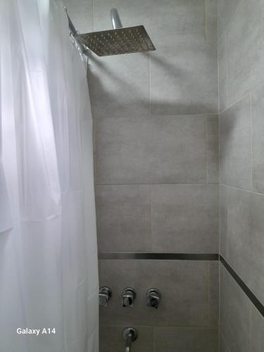 a shower with a white shower curtain and a shower head at Casa Juani in Quequén