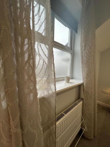 a window with a curtain next to a radiator at Modern 2Bed Netflix & Free Parking Telford Gem in Dawley