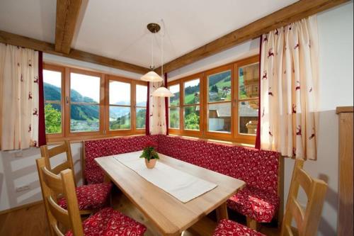 a dining room with a table and a red couch at Tauernchalets in Grossarl