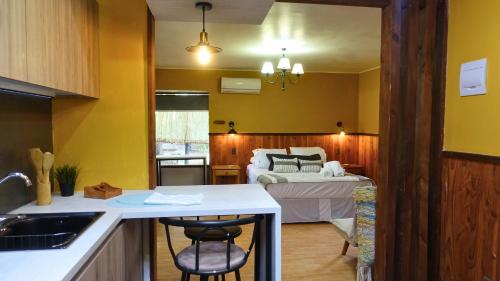 a kitchen with yellow walls and a bedroom with a bed at Estero El Claro Hotel y Cabañas in Pucón