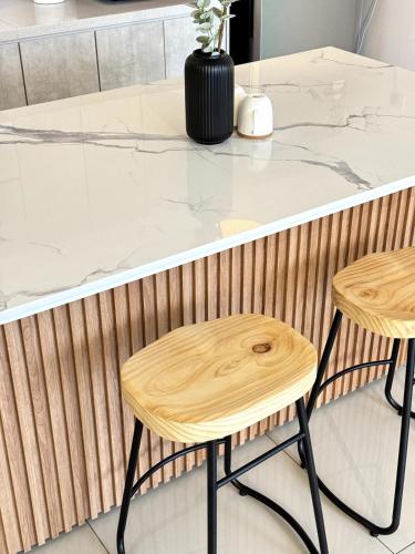a kitchen with two stools at a counter at Nature & Pool view Condo 3R3B IOI Resort Putrajaya in Putrajaya