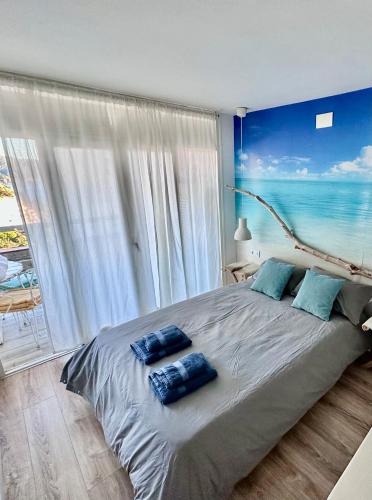 a bedroom with a large bed with two blue pillows on it at Chalana II, Cala Salions, Tossa de Mar in Tossa de Mar