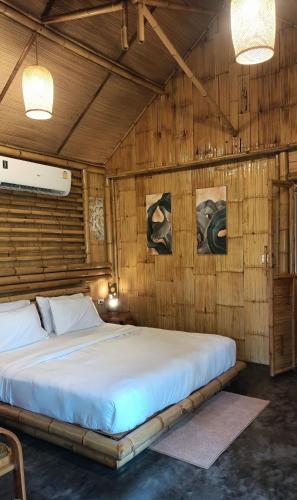a large bed in a room with wooden walls at สวนเกษตรรักษ์ไผ่ Bamboo Conservation Farm in Surin