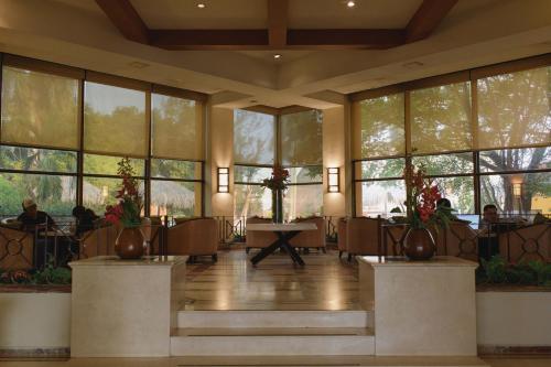 a lobby with tables and chairs and large windows at Hotel Terranova in Coatzacoalcos