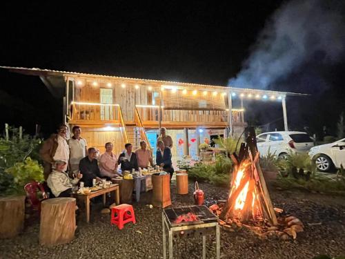 a group of people sitting around a fire in front of a building at Thanh Bình Homestay Măng Đen in Kon Von Kla