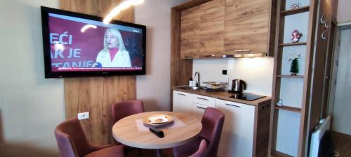 a room with a table and a tv on the wall at Apartments KOP Konaci in Kopaonik