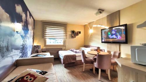 a room with a bed and a table and a tv at Apartments KOP Konaci in Kopaonik