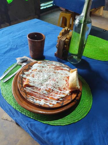 a pizza on a plate on a table with a bottle at Temazcal Casa de Barro in San Juan Teotihuacán
