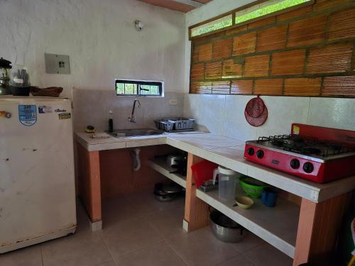 a kitchen with a stove and a sink and a refrigerator at Cabaña Campestre de Descanso in Melgar