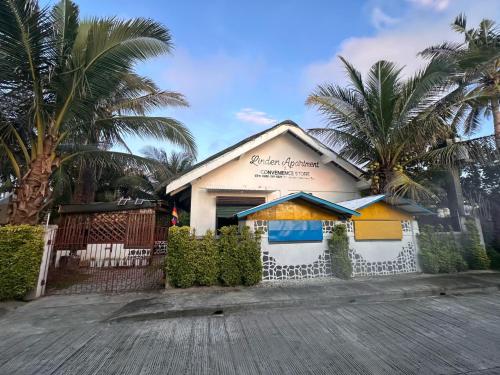 a building with a fence and palm trees on a street at Linden Apartment in Biri
