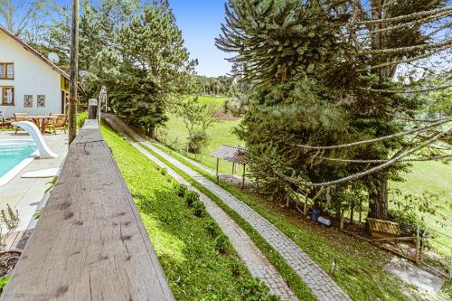 a wooden walkway next to a swimming pool next to a house at Chale - Cabana próximo Curitiba in Piraquara