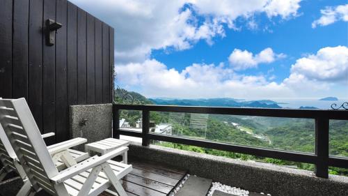 two white chairs sitting on a balcony with a view at Sunny Room in Jiufen