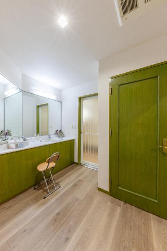 a bathroom with a green door and a chair at Hotel Furano Verde in Furano
