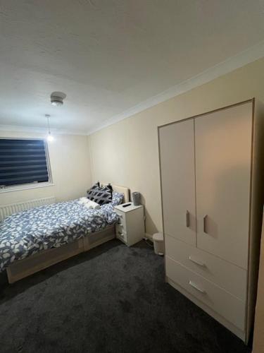 a bedroom with a bed and a cabinet in it at Barnfield Rooms in Chelmsford