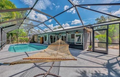 a glass house with a hammock in front of a pool at Enchanted & peaceful Oasis 10 min away from one of the most beautiful beaches in the World Siesta key in Sarasota