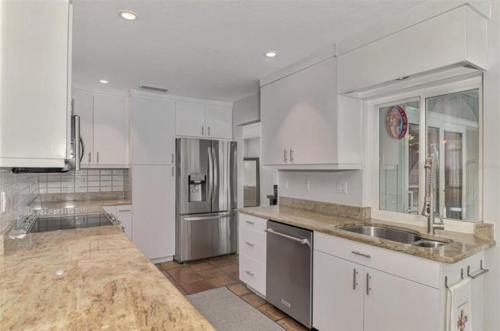 サラソタにあるEnchanted & peaceful Oasis 10 min away from one of the most beautiful beaches in the World Siesta keyの白いキャビネットとステンレス製の冷蔵庫を備えたキッチン