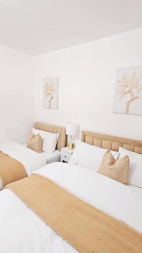 two beds in a room with white walls at Cosy and stylish 3 bedroom house in Middleton