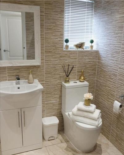 a bathroom with a white toilet and a sink at Cosy and stylish 3 bedroom house in Middleton