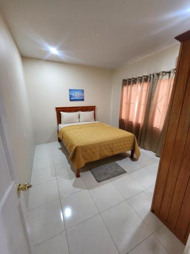 a small bedroom with a bed with a yellow bedspread at AG3K Oasis in Buccoo