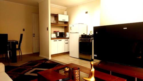a living room with a tv and a kitchen at Estadía Bertita in Talca