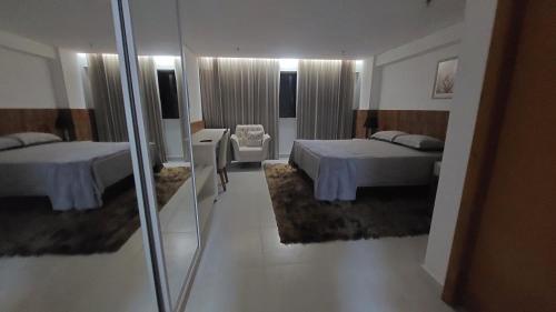 Una habitación de hotel con dos camas y un espejo. en Suíte em Cosmopolitan Home e Office em Palmas, en Palmas