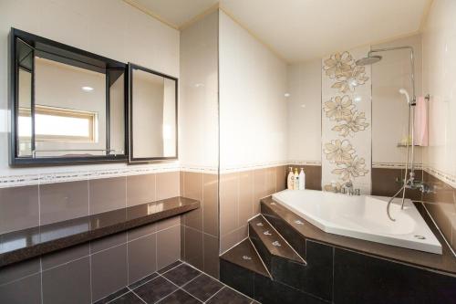 une salle de bain avec une baignoire, un lavabo et un miroir dans l'établissement 제주동쪽숙소 제주곶자왈별장 ForestGarden TheHouseOfCottonClouds, à Jeju