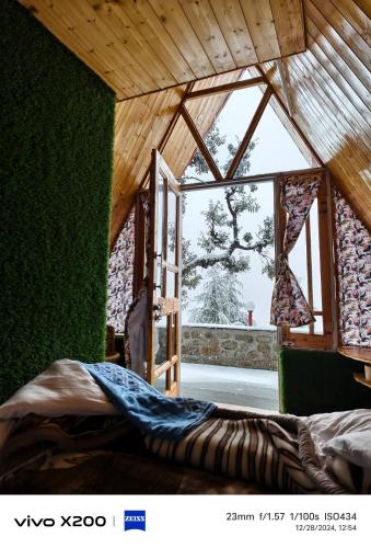 a room with a green wall and a large window at Eva Cabins in Dalhousie