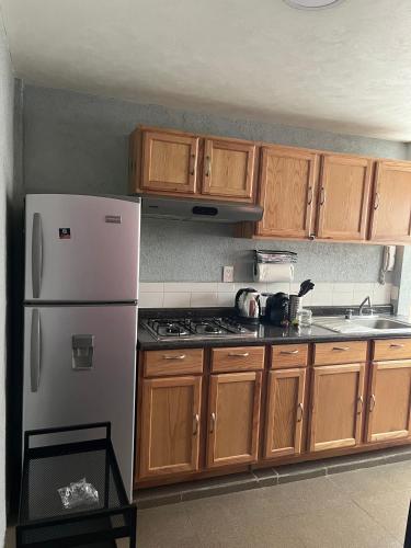 a kitchen with wooden cabinets and a white refrigerator at Departamento Rompecabezas SúperAnfitrión Coyoacan in Mexico City