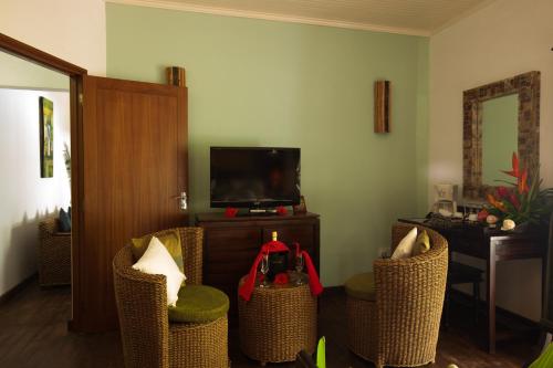 a living room with wicker chairs and a television at Le Relax Beach Resort in Grand'Anse Praslin