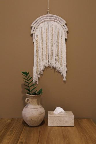 a chandelier hanging over a table with a plant in a vase at baan nuit Bangkok Stayhouse in Bangkok