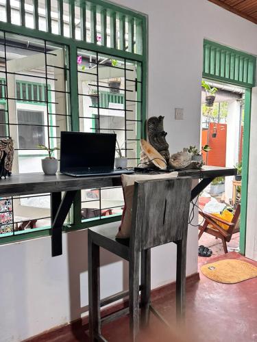 a desk with a laptop and a chair in a room at The Fort Library Hostel in Galle