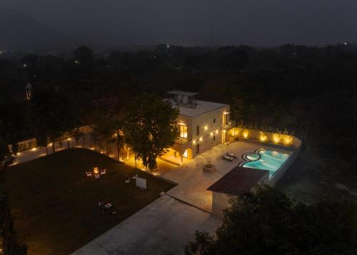 an aerial view of a house with a swimming pool at night at SaffronStays Pristine Manor - 8-BR Udaipur villa with private pool, garden, and event space near Fateh Sagar Lake in Udaipur